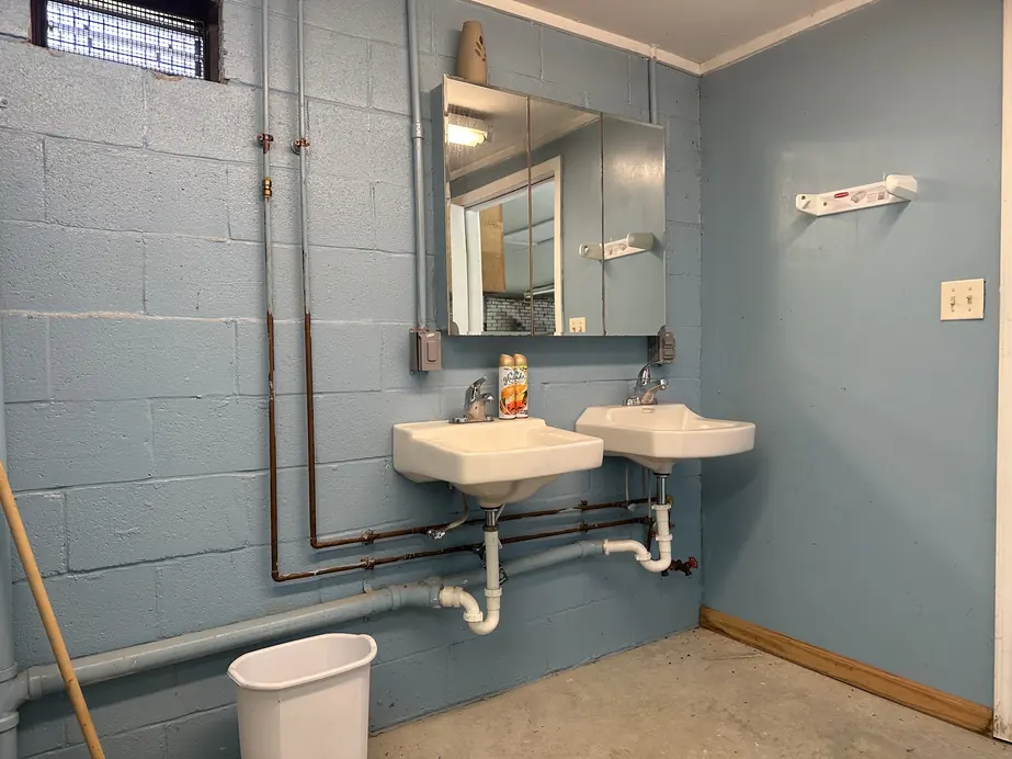 Bath house interior with a row of sinks against a blue block wall