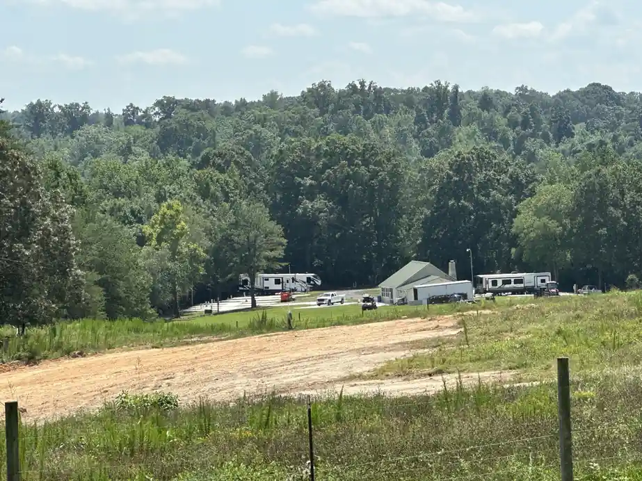 Meadow above the park with the clubhouse and RVs on the far pad area below the tree line