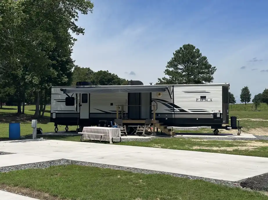 Travel trailer with its awning out on a fresh concrete pad beside new lawn