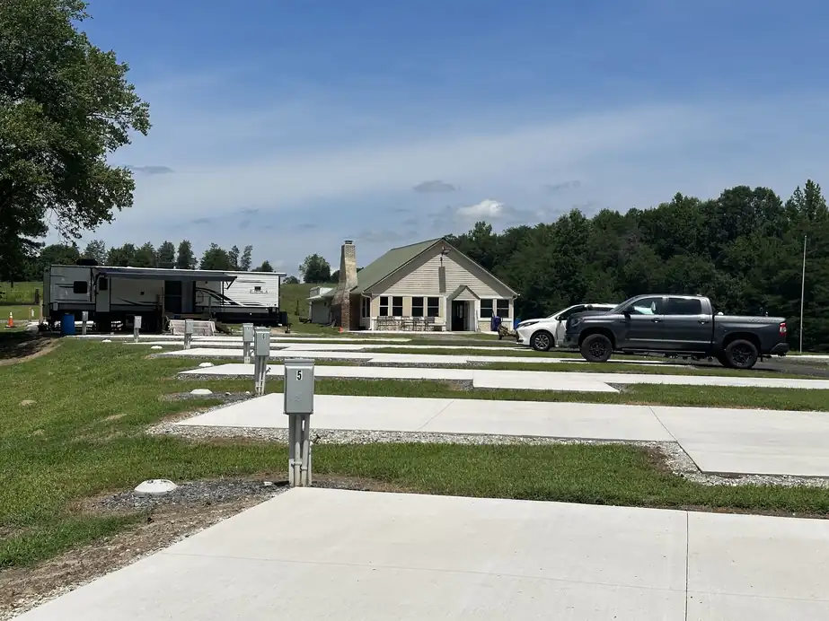 Row of empty concrete RV pads with utility pedestals and the clubhouse behind